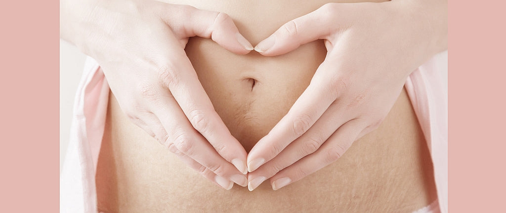 Unterkörper einer Frau nach Schwangerschaft mit Händen davor die ein Herz formen