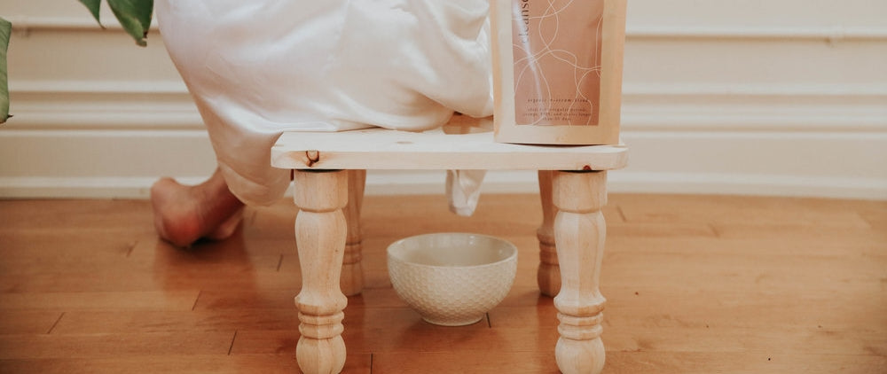 Yoni Steaming: Frau sitzt auf einem kleinen Hocker über einer Schale