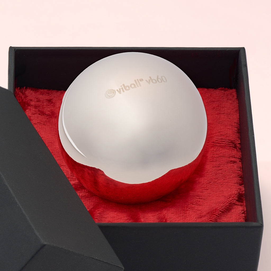 Primer plano de una Viball VB60 bola china médica de 60 mm de acero inoxidable antialérgico para mujeres y hombres en una caja negra sobre terciopelo rojo.