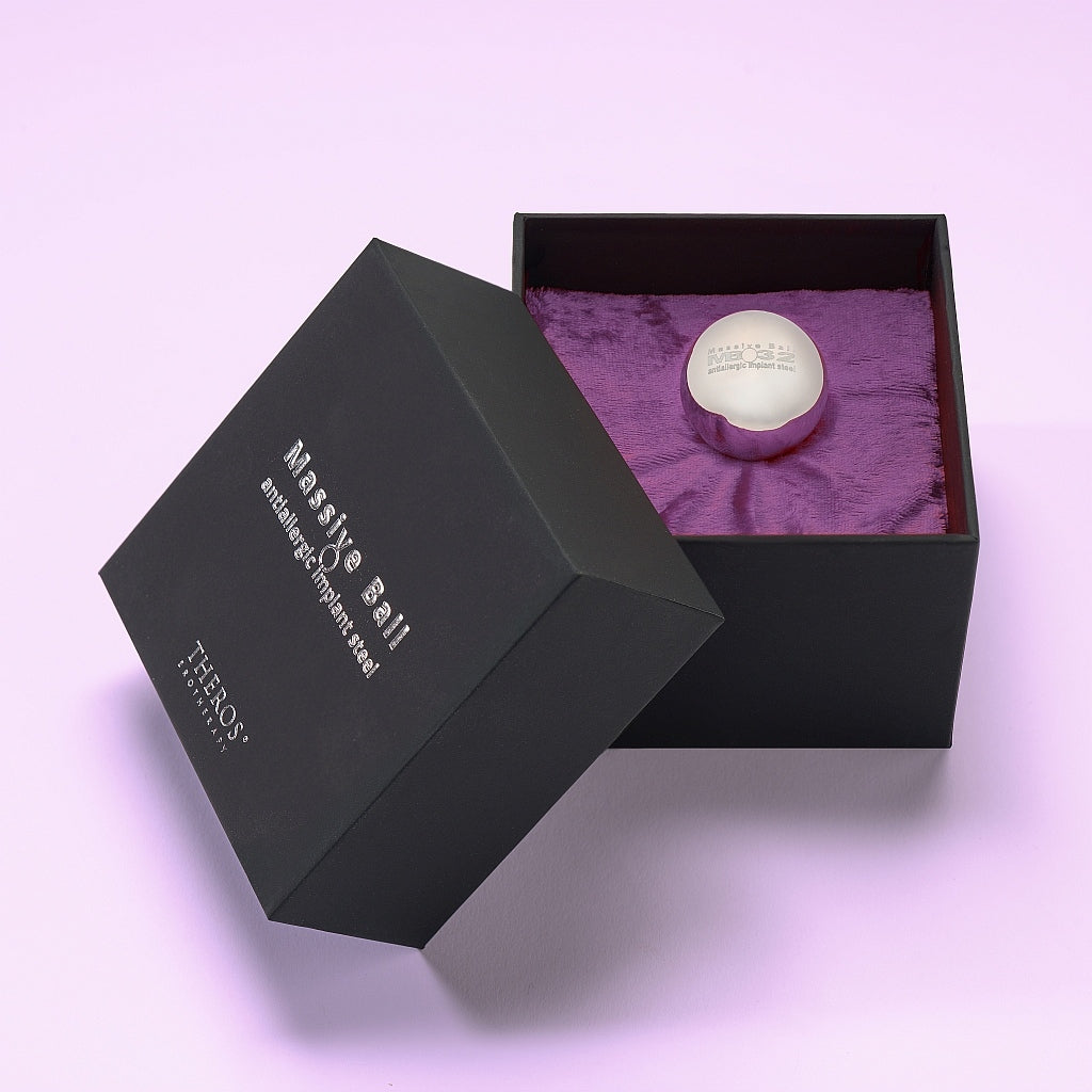 Theros® Massive Ball MB32 – esfera maciza de 32 mm de acero inoxidable antialérgico para mujeres y hombres para el entrenamiento del suelo pélvico en posiciones horizontales o para la estimulación de la próstata en una caja negra sobre terciopelo violeta oscuro.