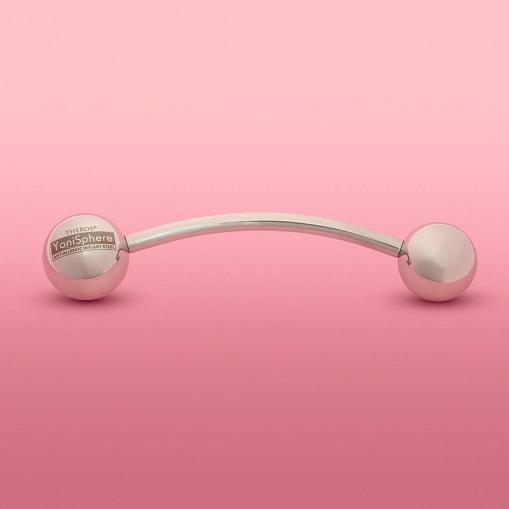 YoniSphere Theros® YS40: Dispositivo de masaje ergonómico para el suelo pélvico y la vagina para la relajación física y mental, compuesto por una varilla ligeramente curvada con una bola de 45 mm como mango con logotipo en un lado y una bola de masaje intercambiable de tamaño 40 mm en el otro lado. Vista frontal.