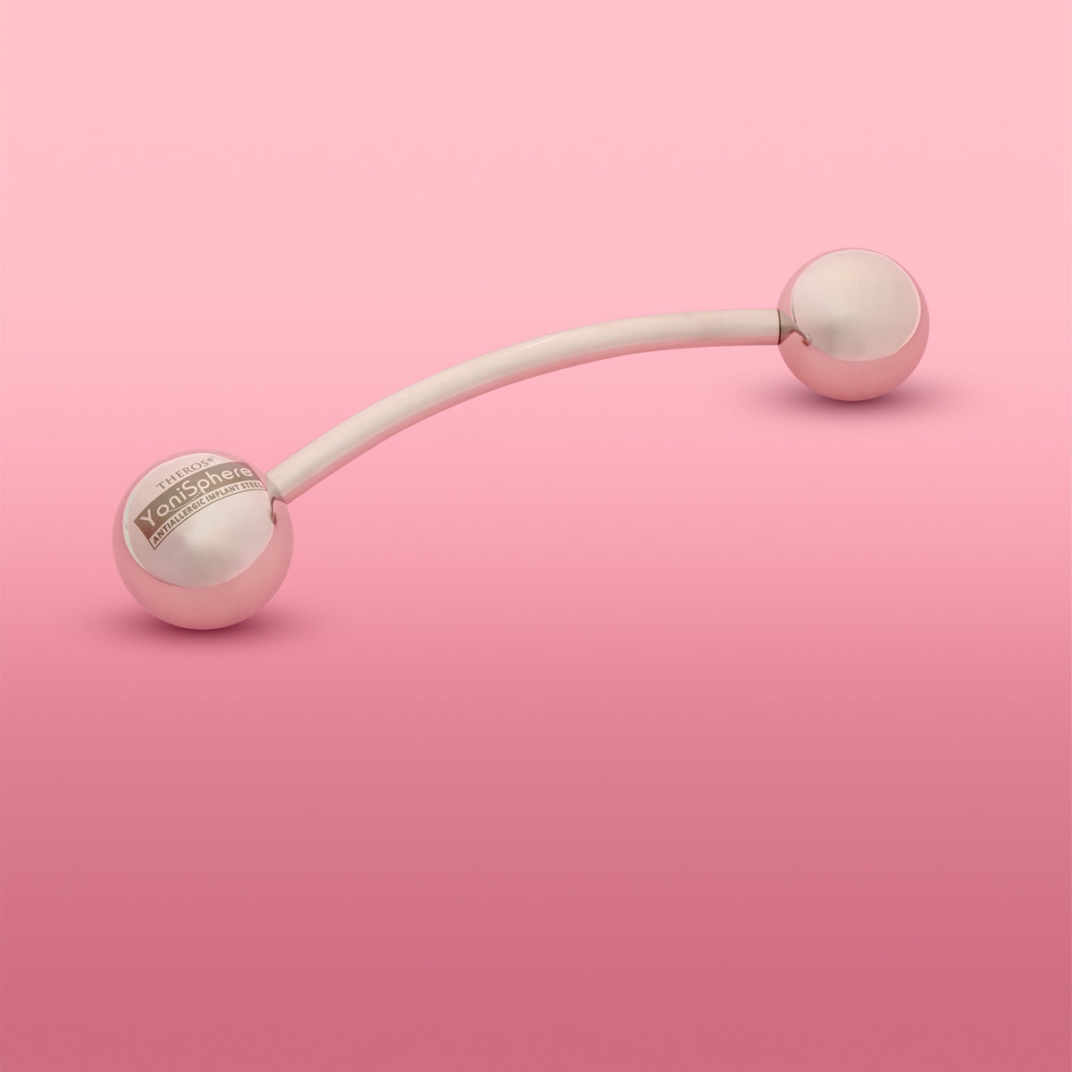 YoniSphere Theros® YS40: Dispositivo per massaggio ergonomico per il pavimento pelvico e la vagina per il rilassamento fisico e mentale, composto da un’asta leggermente curva con una sfera da 45 mm come impugnatura con logo su un lato e una sfera da massaggio intercambiabile di dimensione 40 mm sull’altro lato. Vista da sinistra.

