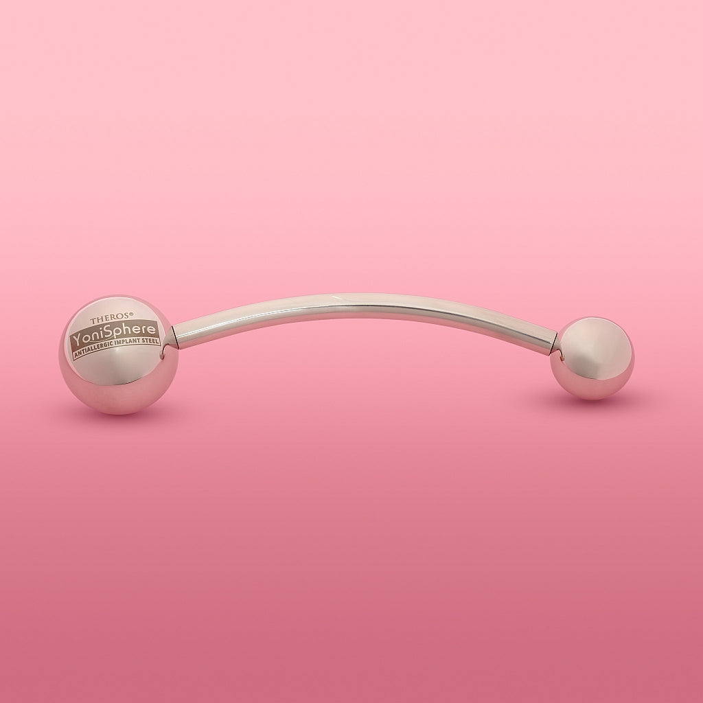 Theros(R) Yonisphere 32: Innovatives Hilfsmittel aus poliertem edelstahl für Dammmasssage, Beckenbodenmassage, Probleme in der Vagina wie Geburtsverletzungen, Endometriose und Hämorrhoiden bei Frauen bestehend aus aufschraubbaren Massagekugeln in verschiedenen Größen an einer gebogenen Stange. Rosa Hintergrund.