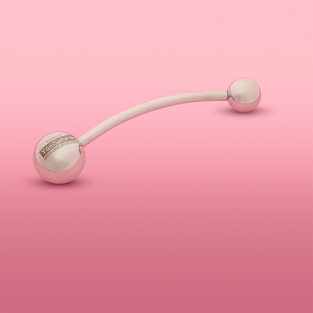 Theros(R) Yonisphere 32: Innovatives Hilfsmittel aus poliertem edelstahl für Dammmasssage, Beckenbodenmassage, Probleme in der Vagina wie Geburtsverletzungen, Endometriose und Hämorrhoiden bei Frauen bestehend aus aufschraubbaren Massagekugeln in verschiedenen Größen an einer gebogenen Stange. Rosa Hintergrund.